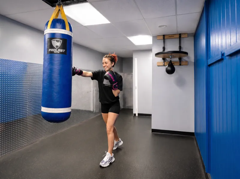 A member in boxing gloves throwing a punch at a heavy bag in the Boxing Studio at Foundation Fitness Annapolis